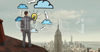 Rear view of businessman on roof drawing clouds and bulb in midair