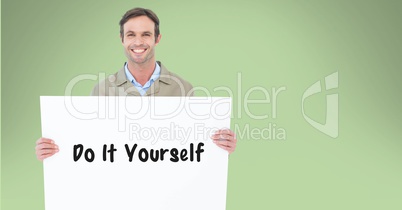 Portrait of man holding billboard with do it yourself text against green background
