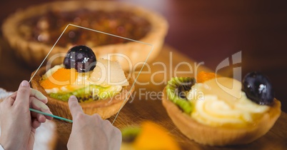 Hands taking picture with transparent device in bakery