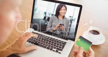 Person using card while video conferencing with businesswoman on laptop