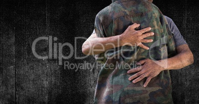 Soldier hugging mid section against black wood panel and grunge overlay