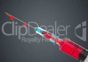 Syringe with red liquid against grey background