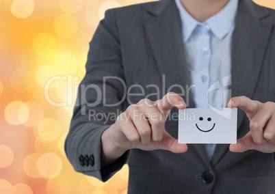 Midsection of professional holding business card with smiley face over bokeh