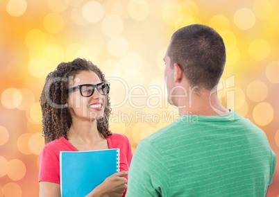 Happy businesswoman holding book while looking at male colleague over bokeh