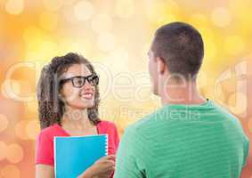 Happy businesswoman holding book while looking at male colleague over bokeh