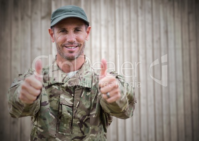 Soldier thumbs up against blurry wood panel
