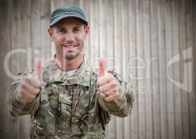 Soldier thumbs up against blurry wood panel
