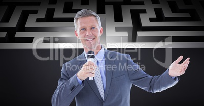 Confident businessman holding microphone against maze