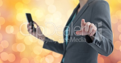 Midsection of businesswoman pointing while holding mobile phone