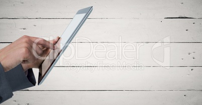 Hands touching tablet against white wood panel