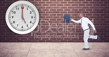 Businessman with briefcase running late with clock mounted on wall