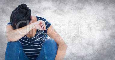 Woman sitting and crying into arm against white wall with grunge overlay