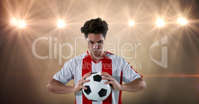 Soccer player holding ball at illuminated stadium