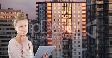 Thoughtful young woman holding tablet PC in city