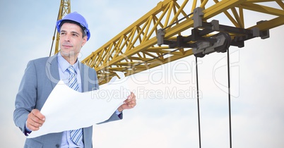 Male architect holding blueprint against crane