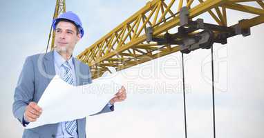 Male architect holding blueprint against crane