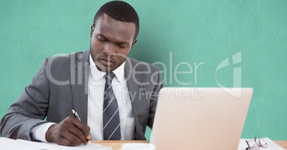 Businessman writing at desk over green background