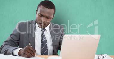Businessman writing at desk over green background