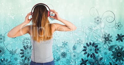 Rear view of woman listening to songs on headset against floral pattern