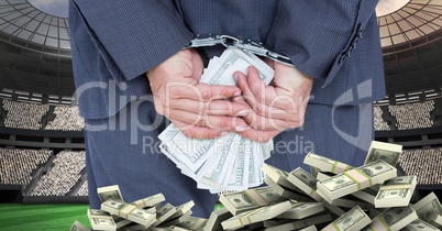 Hands with handcuffs and money at football stadium representing corruption
