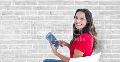 Smiling woman using tablet PC against wall