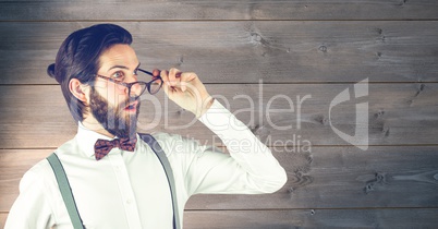 Shocked hipster wearing eyeglasses against wooden wall