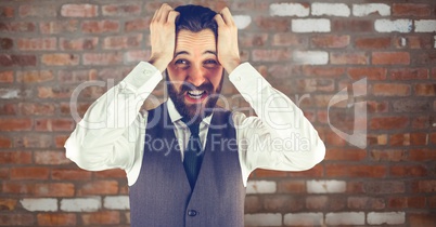 Businessman pulling hair against brick wall