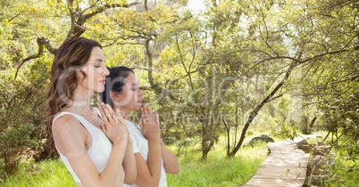 Double exposure of women with hands clasped meditating in forest