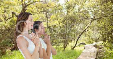 Double exposure of women with hands clasped meditating in forest