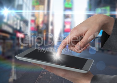 Hands touching tablet against blurry street with flares and bokeh