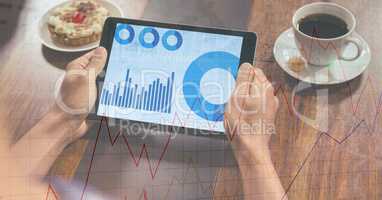 Hands holding digital tablet displaying graphs with overlay