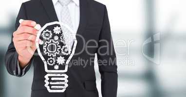 Business man mid section drawing lightbulb doodle against blurry grey office