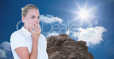 Shocked businesswoman against rock on sunny day
