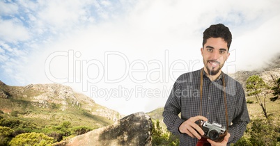 Portrait of smiling male hiker holding camera on mountain