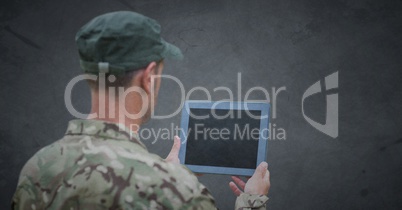 Back of soldier with tablet against grey background with grunge overlay