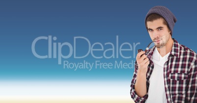 Confident male hipster smoking pipe against blue background