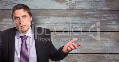 Portrait of businessman shrugging shoulders against wooden wall