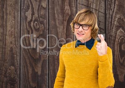 Portrait of smiling male hipster crossing fingers against wooden wall