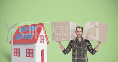 Portrait of delivery man carrying cardboard boxes by house and windmill