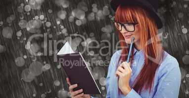 Young woman holding pen while reading book in rainy season