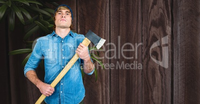 Hipster holding ax against wooden wall