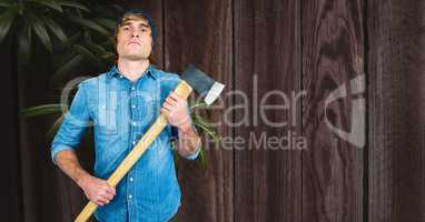 Hipster holding ax against wooden wall