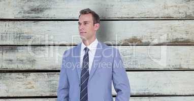 Thoughtful businessman standing against wooden wall