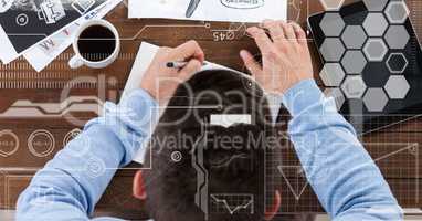 Businessman writing in book by tablet PC and coffee cup