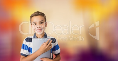 Happy boy holding digital tablet over blur background