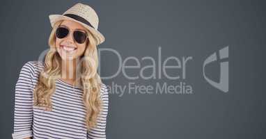 Portrait of happy female hipster wearing sunglasses and sun hat against gray background