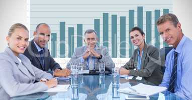 Confident business people at conference table against graph