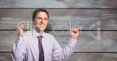 Portrait of successful businessman clenching teeth and fists against wooden wall