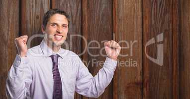 Portrait of successful businessman clenching fists against wooden wall