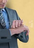 Midsection of businessman touching hand against yellow background